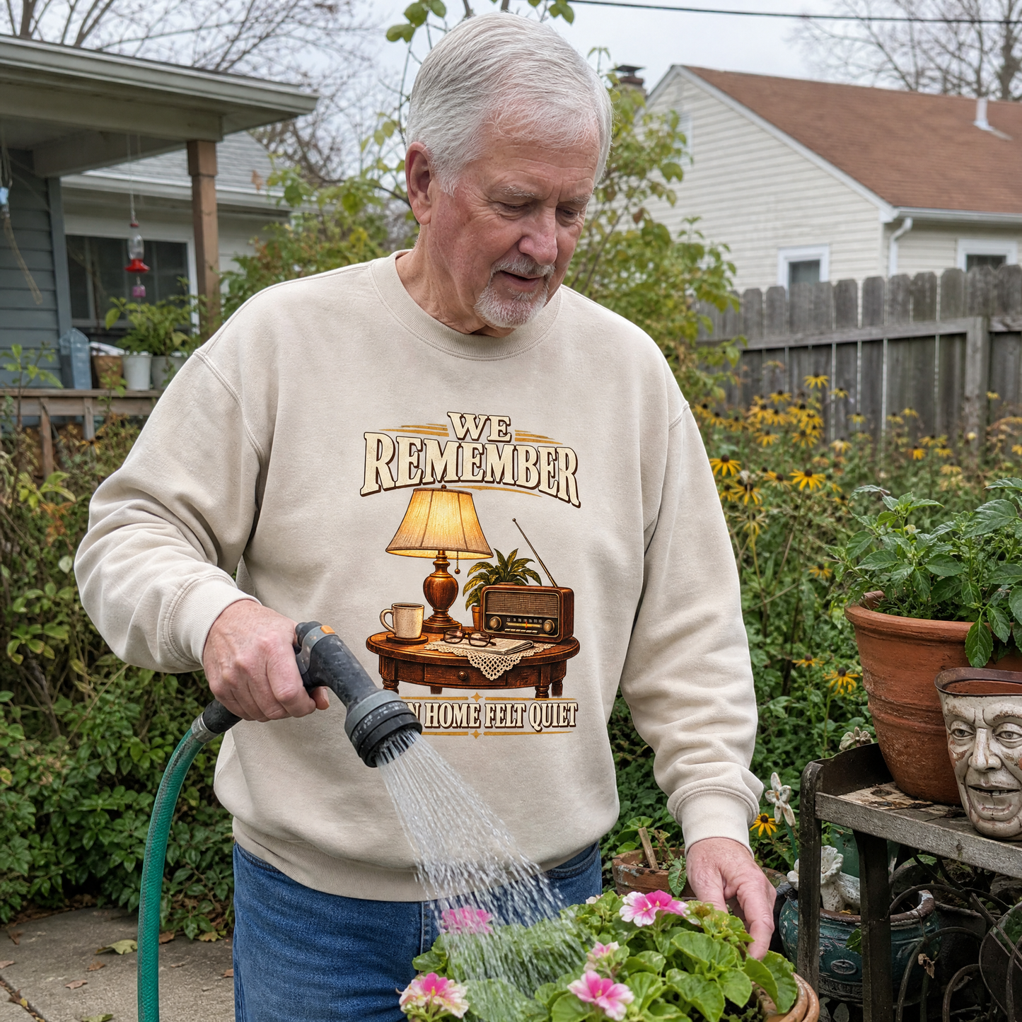 Senior man wearing beige vintage sweatshirt with We Remember Home Felt Quiet print, gardening.