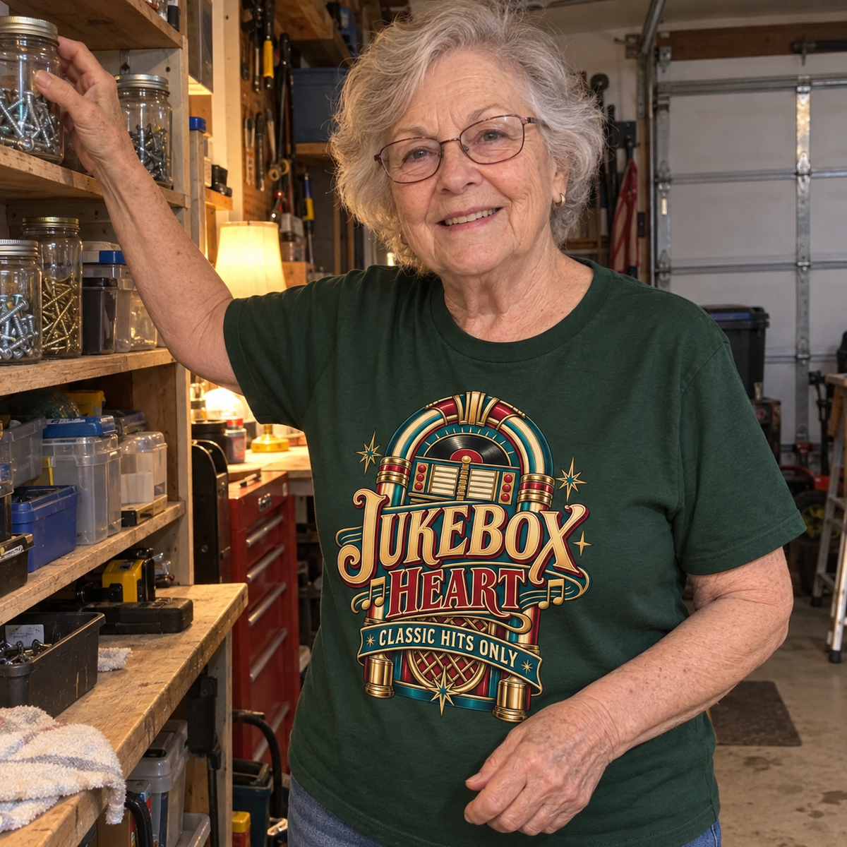 Senior woman in a workshop wearing a green vintage t-shirt printed with a jukebox and “Jukebox Heart Classic Hits Only.”