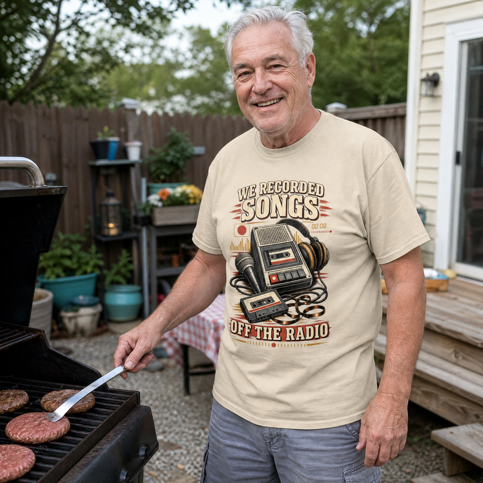 Senior man wearing beige vintage t-shirt with printed radio slogan while grilling outdoors.