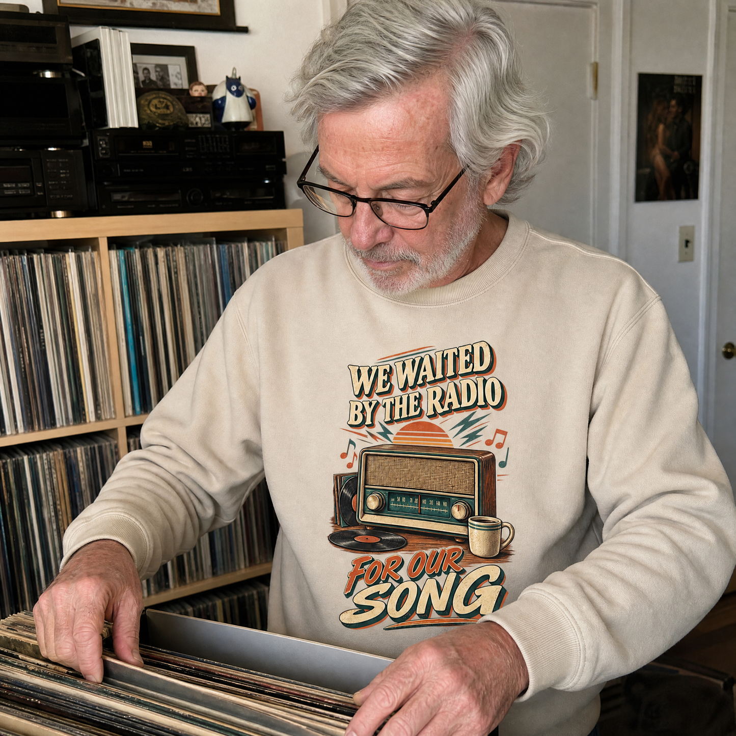 Senior man wearing a beige vintage sweatshirt with printed “We Waited By The Radio For Our Song” design.