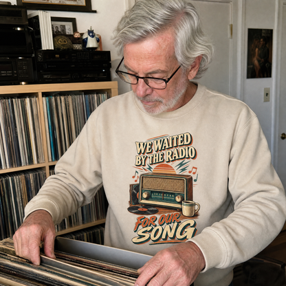 Senior man wearing a beige vintage sweatshirt with printed “We Waited By The Radio For Our Song” design.