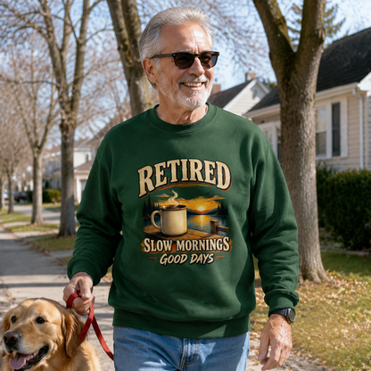 Senior man wearing green vintage sweatshirt with printed “Retired Slow Mornings Good Days” design walking dog.