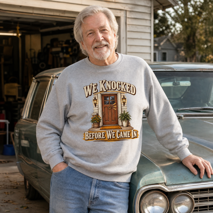 Senior man wearing gray vintage sweatshirt with printed We Knocked design outdoors
