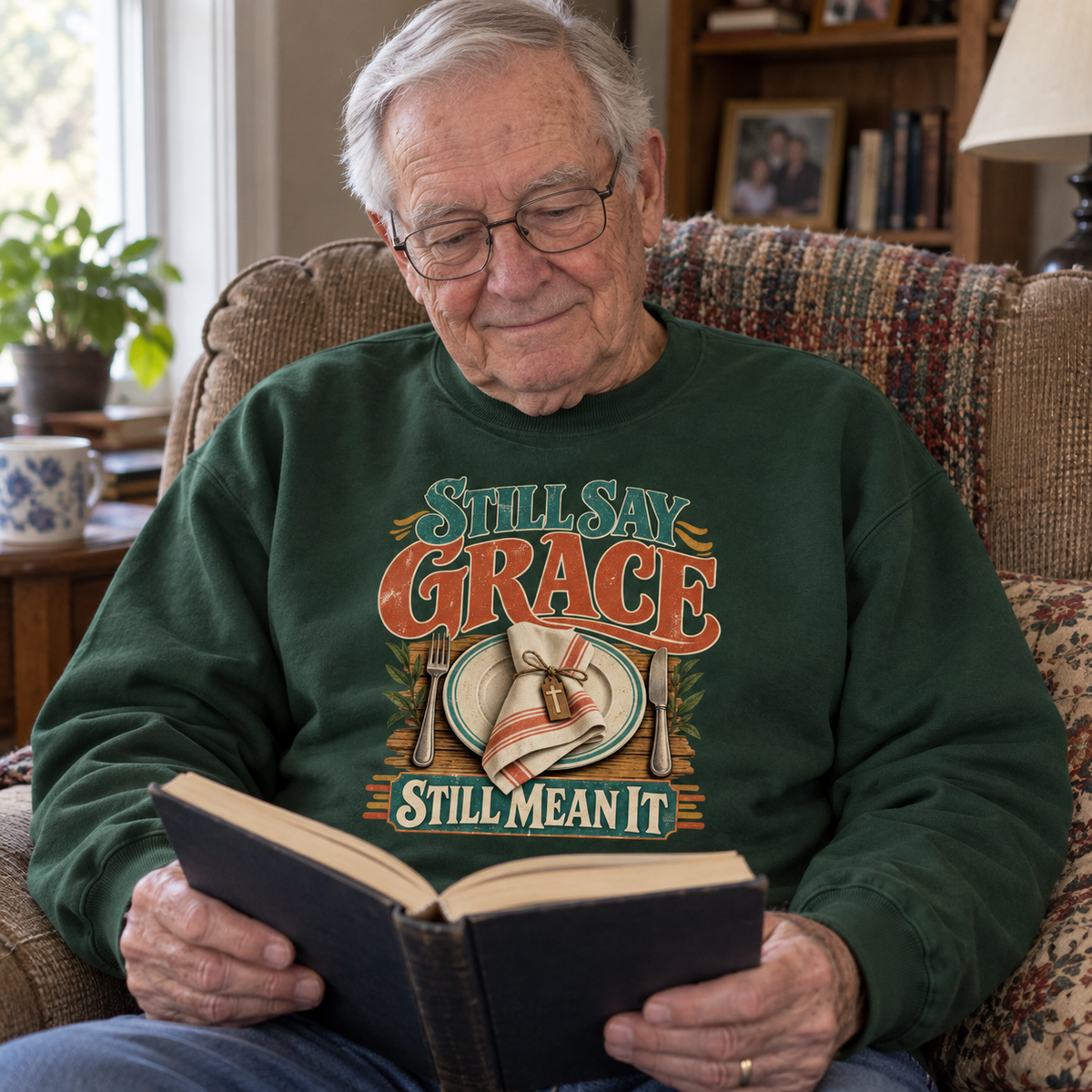 Senior man reading in green vintage sweatshirt printed with Still Say Grace Still Mean It