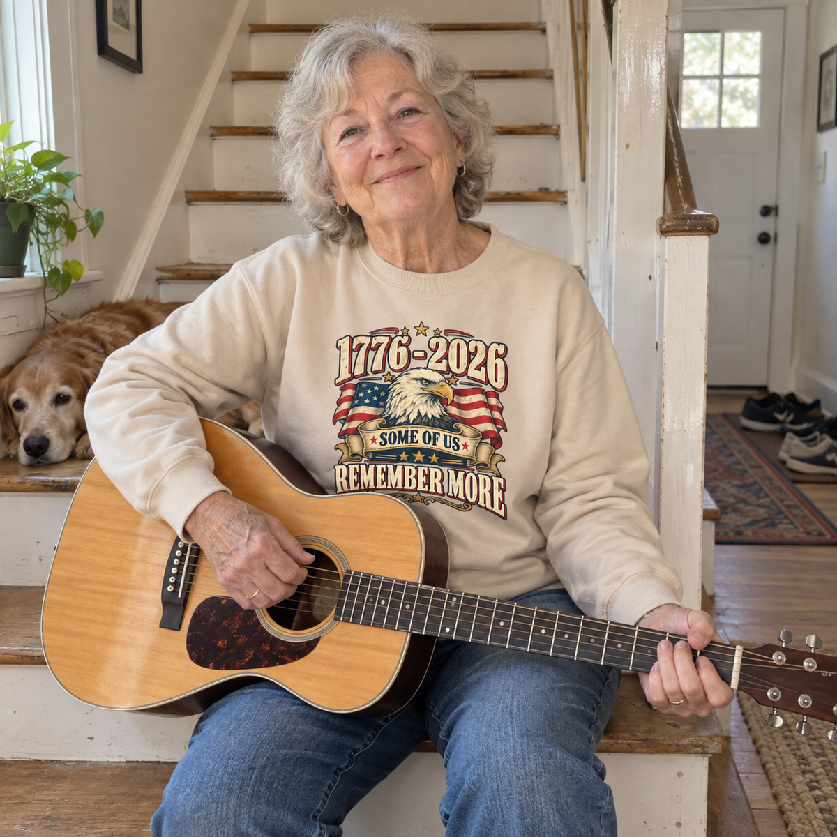 Senior woman holding guitar wears cream vintage sweatshirt printed with 1776-2026 and eagle design
