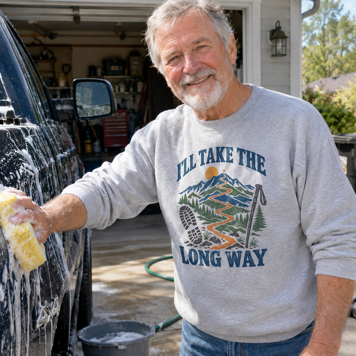 Senior man wearing gray vintage sweatshirt with printed I’LL TAKE THE LONG WAY design outdoors