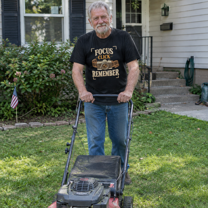 Senior man wears black vintage t-shirt with Focus Click Remember printed design while mowing lawn.