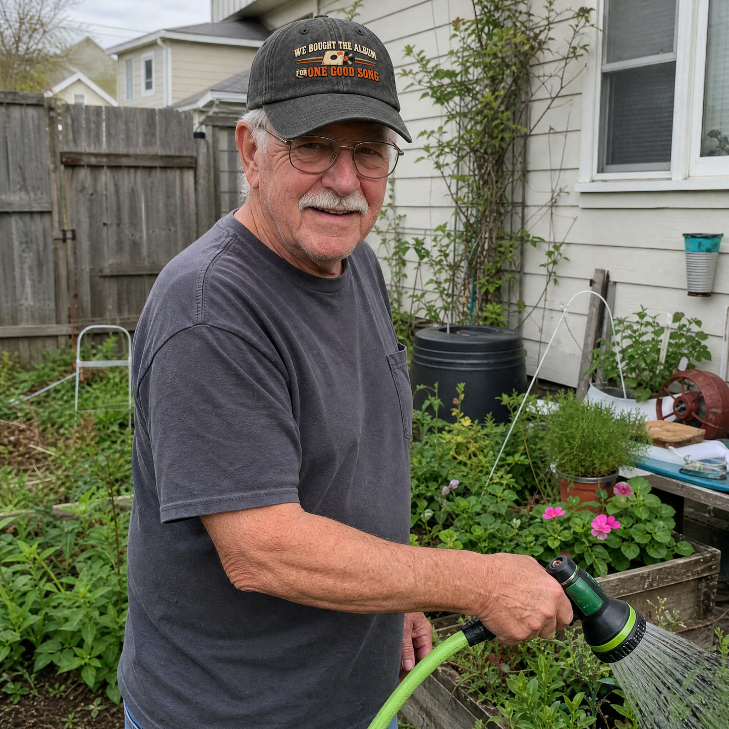 Senior man wearing black vintage washed cap with printed music slogan, watering garden