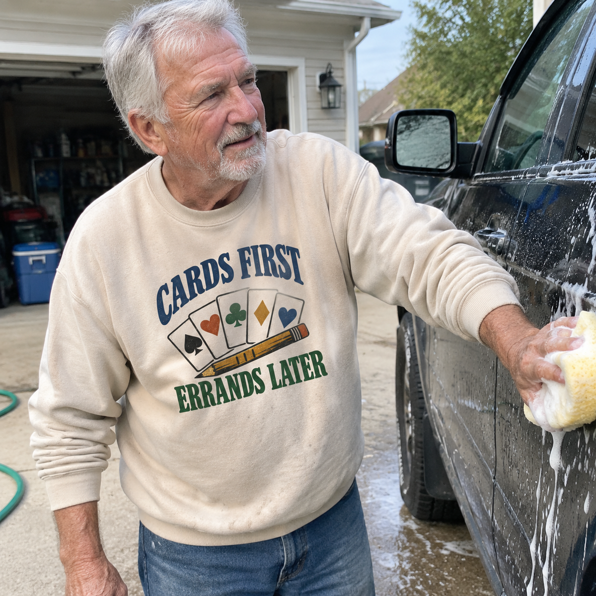 Beige vintage sweatshirt with “Cards First. Errands Later” printed design worn by senior man washing car