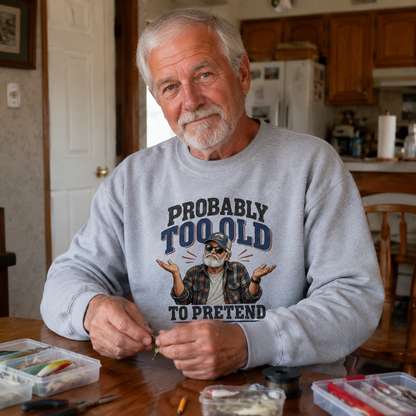 Senior man wearing gray vintage sweatshirt with Probably Too Old To Pretend print at home