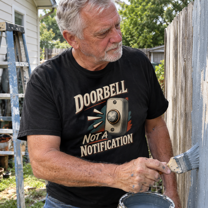 Senior man wearing black vintage t-shirt with Doorbell Not A Notification print, painting fence
