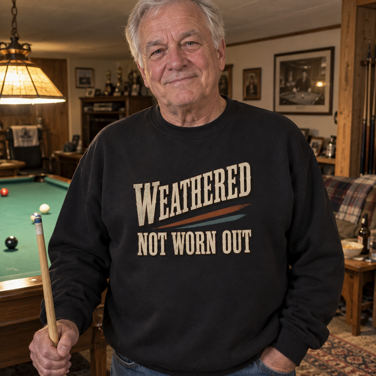 Senior man wearing black vintage sweatshirt with printed Weathered Not Worn Out by pool table