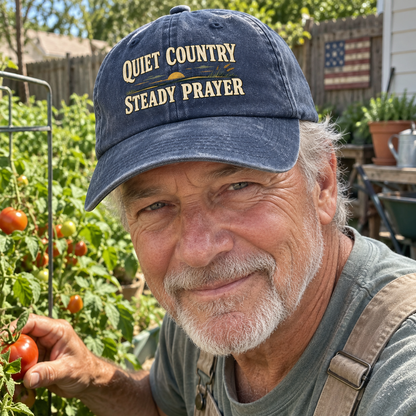 Senior man in garden wears navy vintage washed cap printed Quiet Country Steady Prayer