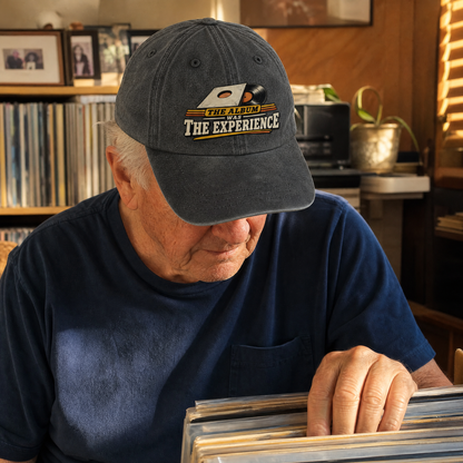Senior man wearing a dark gray vintage washed cap with printed album slogan.