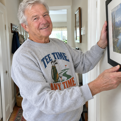 Senior man wearing gray vintage sweatshirt with printed Tee Time Any Time design indoors