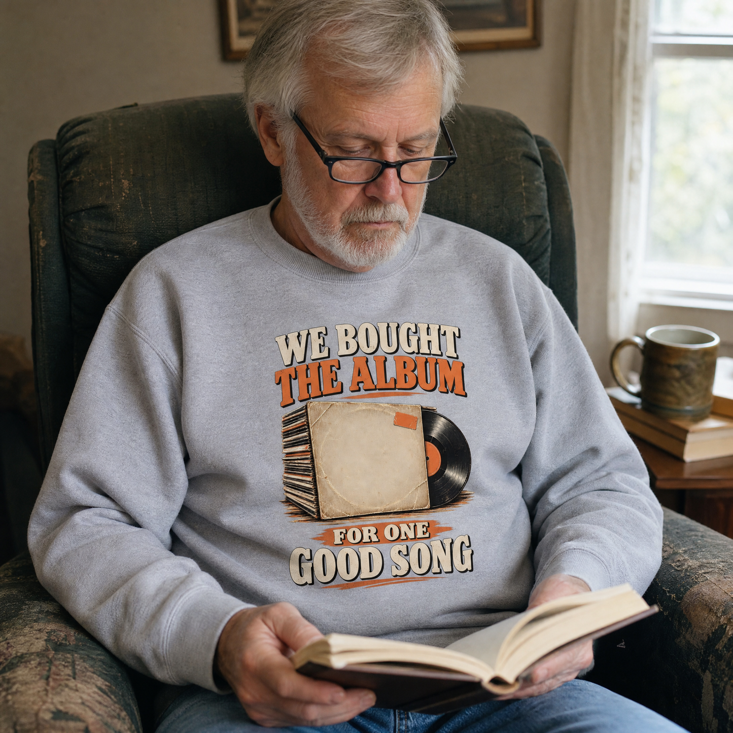 Gray vintage sweatshirt with printed album graphic and slogan worn by senior reading indoors, lifestyle view