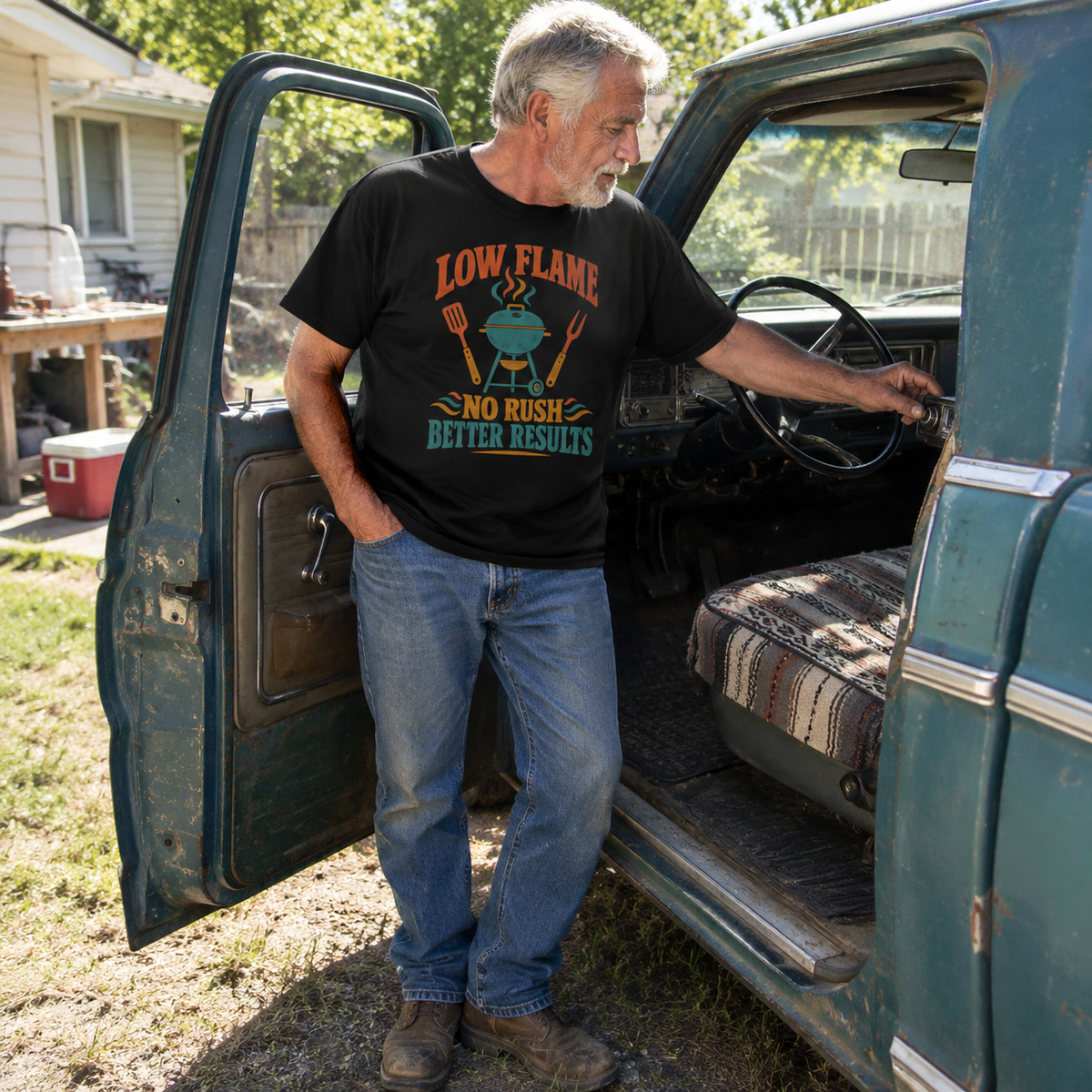 Senior man wearing black vintage t-shirt with printed “Low Flame” slogan beside vintage truck