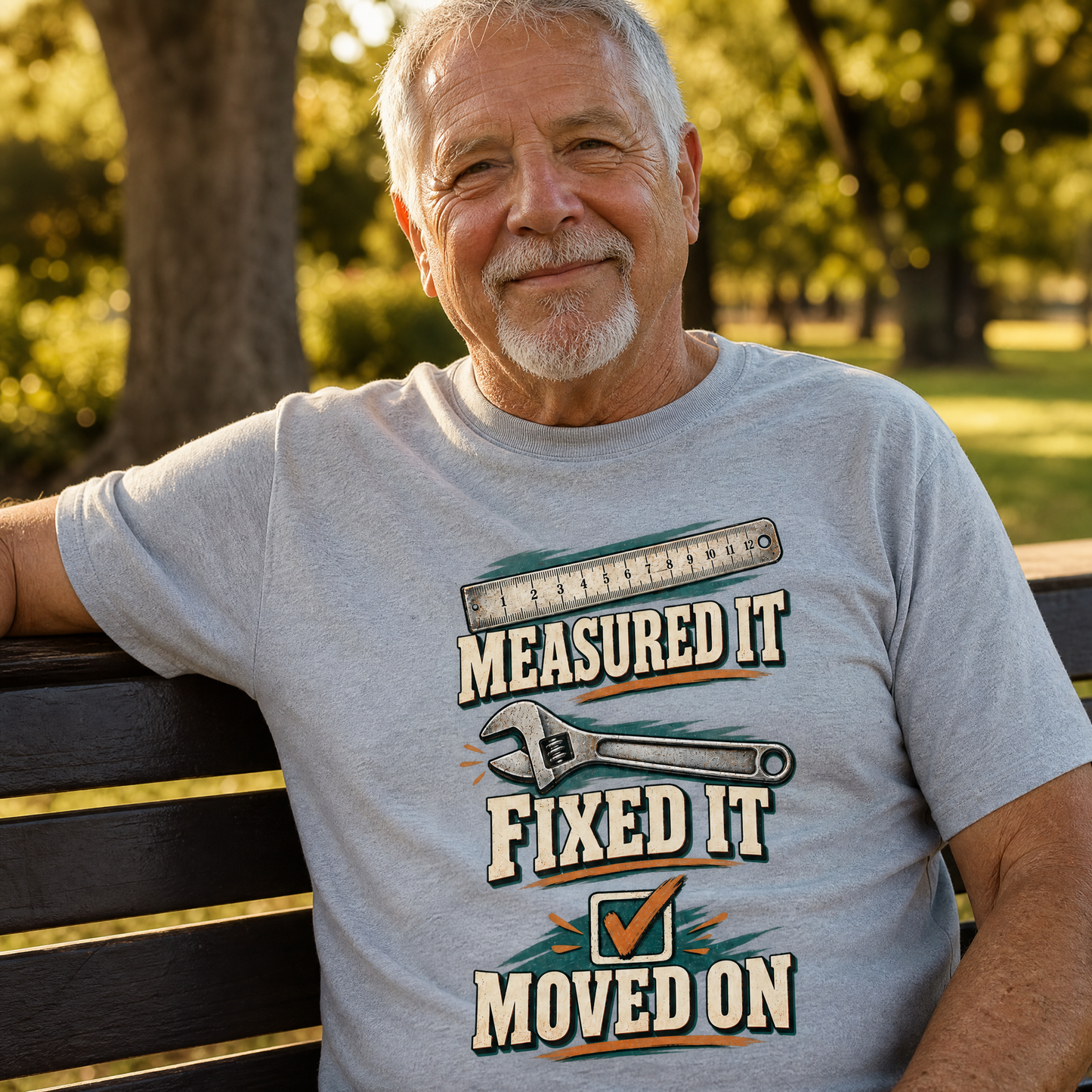 Senior man wearing gray vintage t-shirt printed with “Measured It Fixed It Moved On”