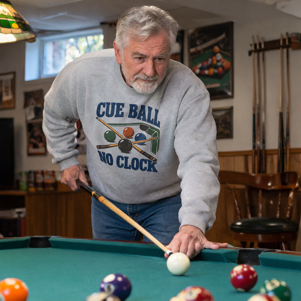 Senior man wearing gray vintage sweatshirt with printed Cue Ball No Clock playing pool