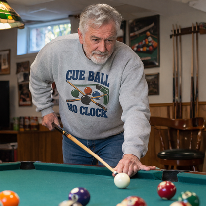 Senior man wearing gray vintage sweatshirt with printed Cue Ball No Clock playing pool