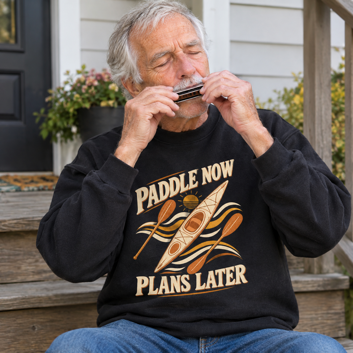 Senior man wearing black vintage sweatshirt with printed Paddle Now Plans Later kayak design, lifestyle view