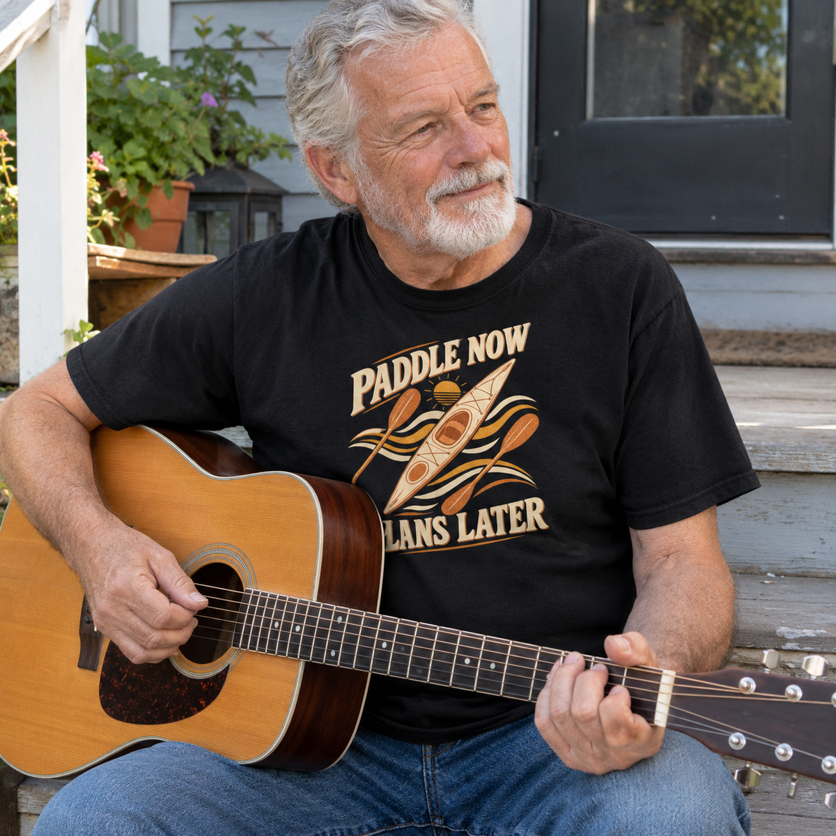 Black vintage t-shirt with Paddle Now Plans Later print worn by senior man playing guitar