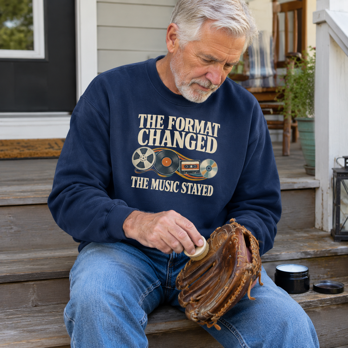 Senior man wearing navy vintage sweatshirt with printed music slogan and retro audio designs, seated outdoors.