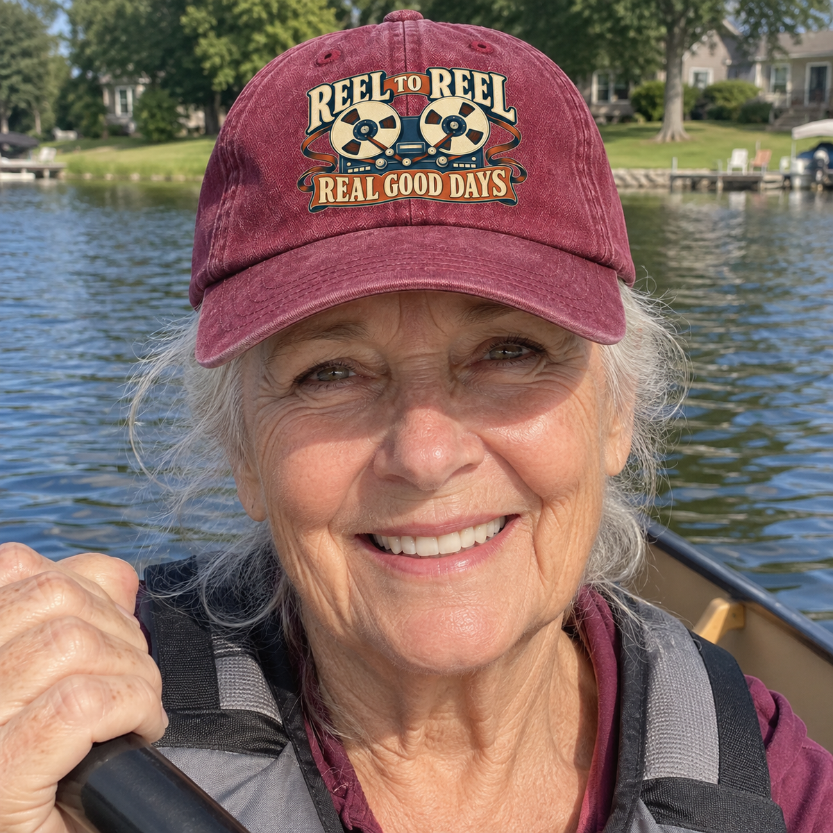 Senior woman lakeside wearing burgundy vintage washed cap with printed tape reels