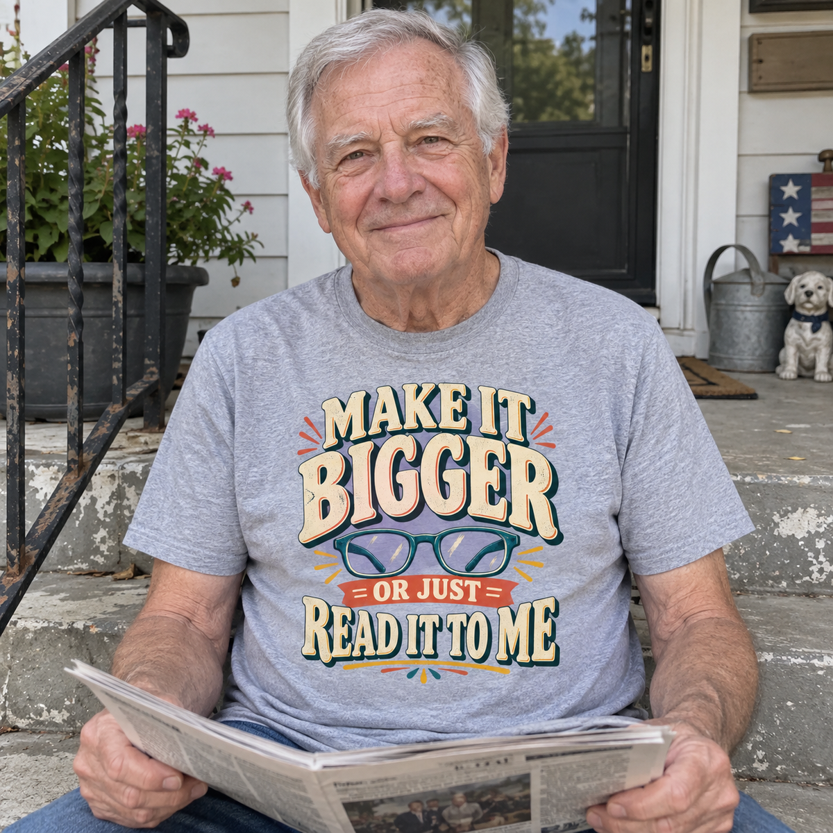 Senior man holds newspaper on porch wearing gray vintage t-shirt with printed glasses slogan