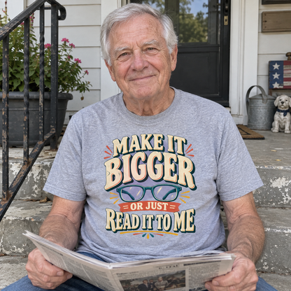 Senior man holds newspaper on porch wearing gray vintage t-shirt with printed glasses slogan