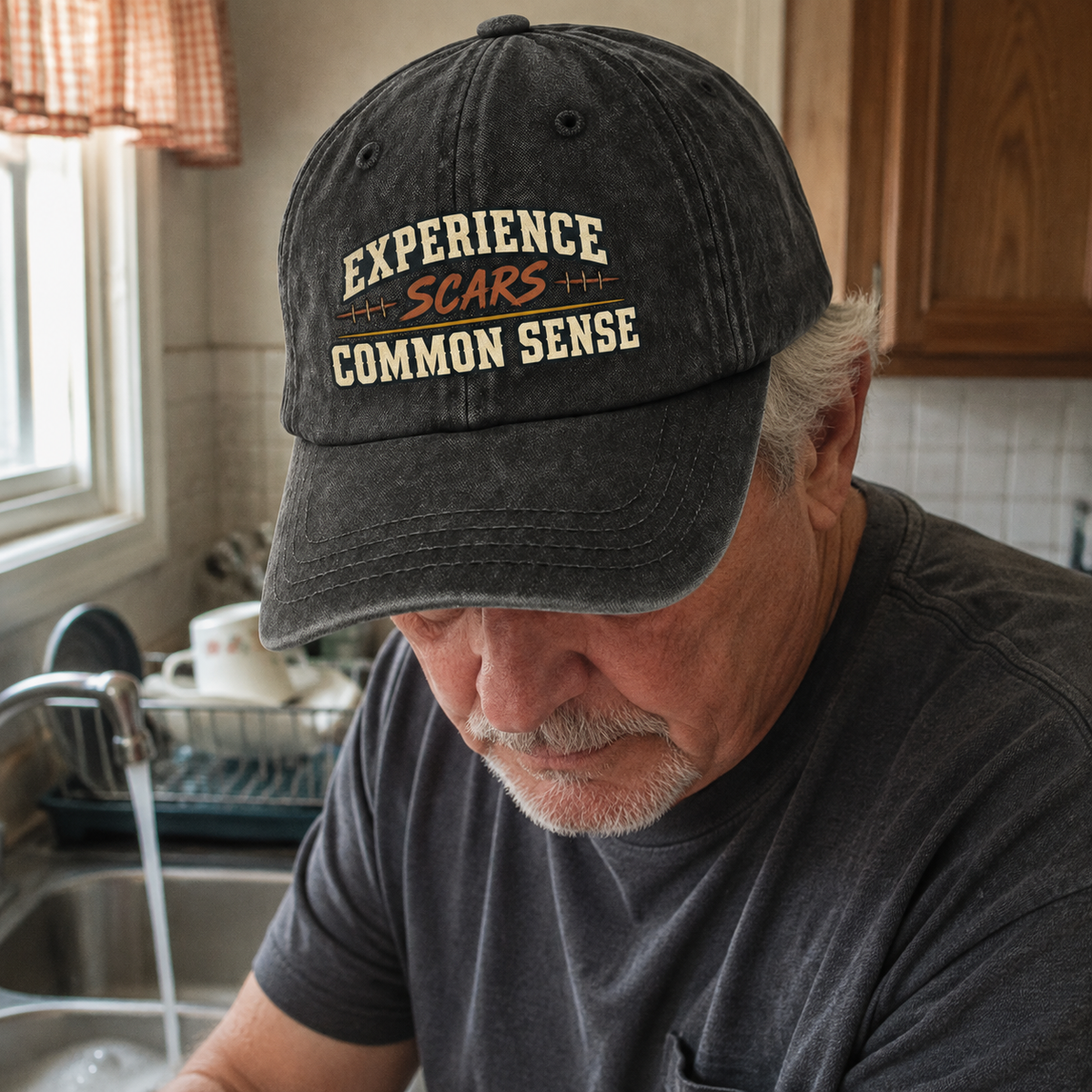 Senior man wearing black vintage washed cap with printed Experience Scars Common Sense slogan indoors