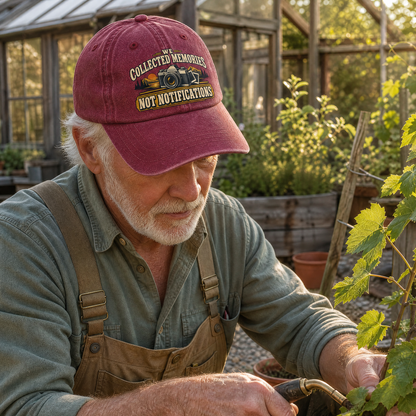 Burgundy vintage washed cap with printed “We Collected Memories Not Notifications” worn by senior gardener