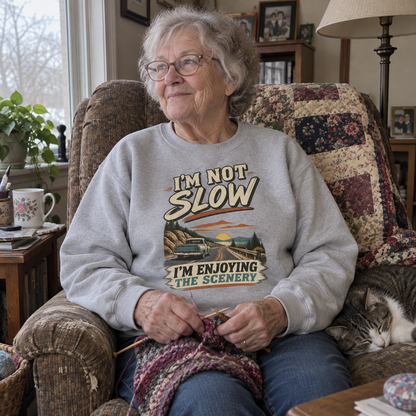 Senior woman knitting beside cat in gray vintage sweatshirt with printed road design