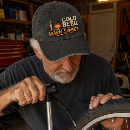 Senior man wearing a vintage washed cap printed with Cold Beer. Warm Sunset while repairing a bicycle.
