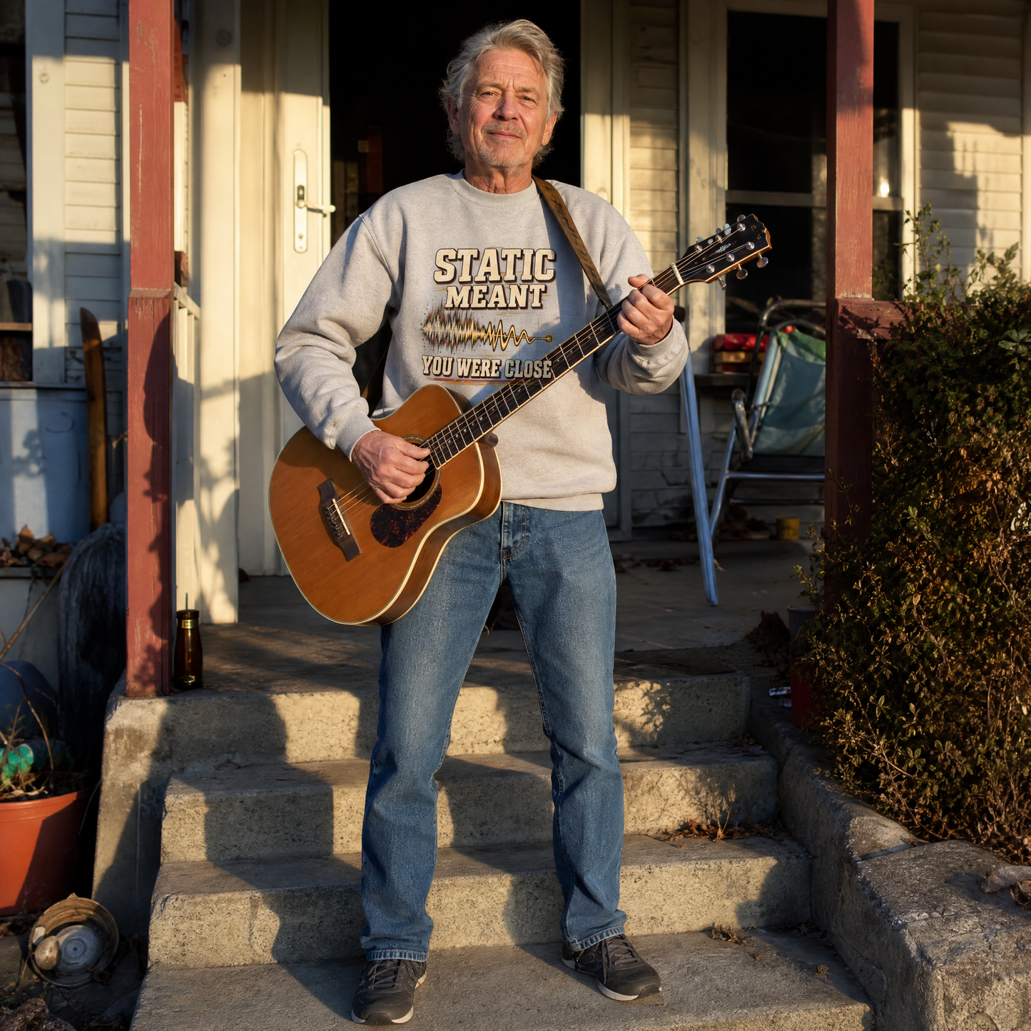 Vintage sweatshirt with printed “Static Meant You Were Close,” worn by senior man playing guitar.