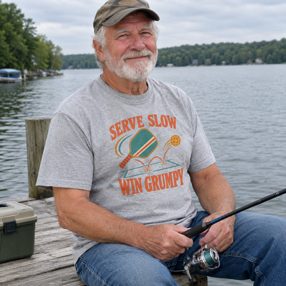 Gray vintage t-shirt with Serve Slow Win Grumpy print worn by senior man fishing lakeside