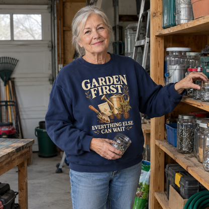 Senior woman wearing navy vintage sweatshirt printed Garden First, Everything Else Can Wait, in workshop