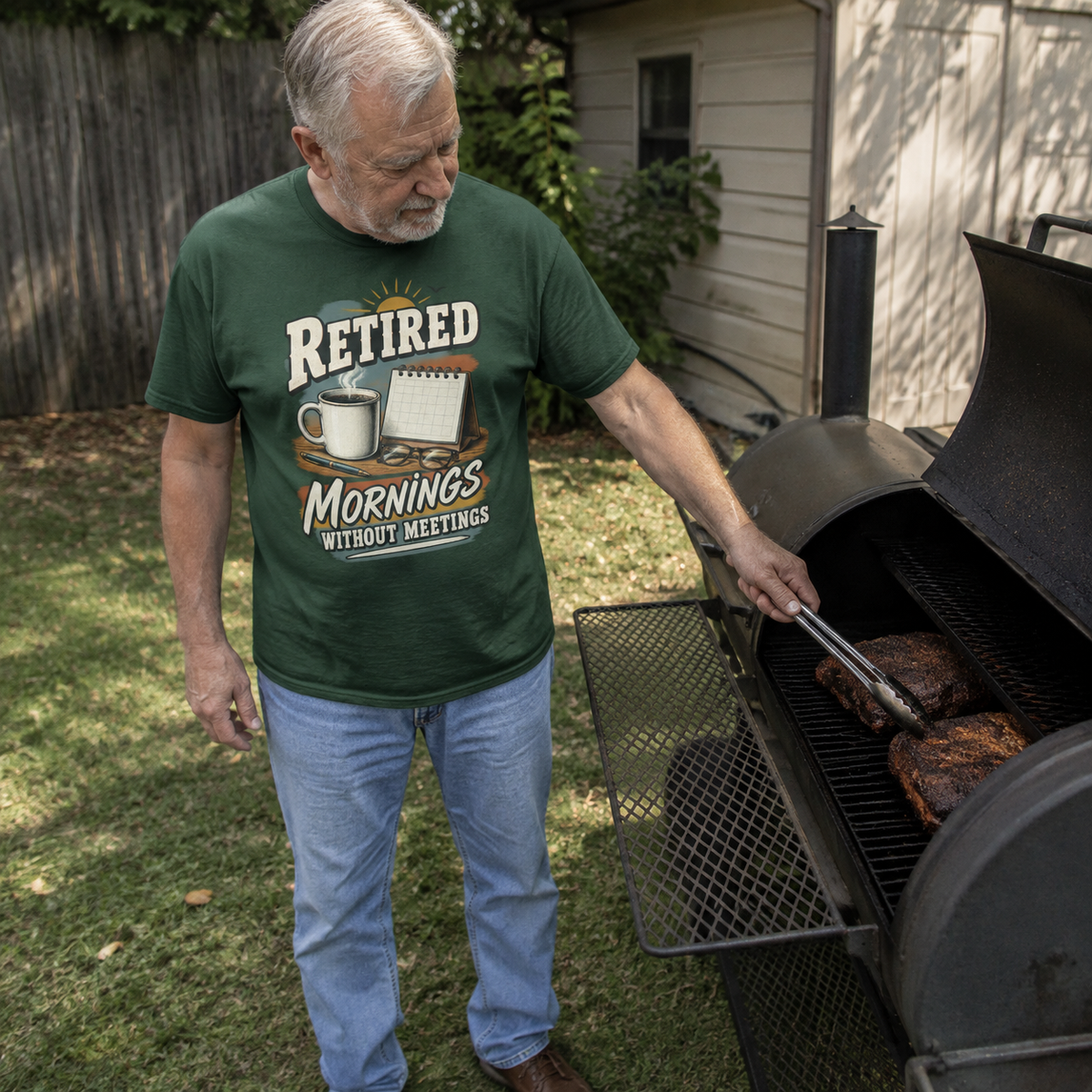 Green vintage t-shirt with printed “Retired Mornings Without Meetings” design worn by senior man grilling outdoors