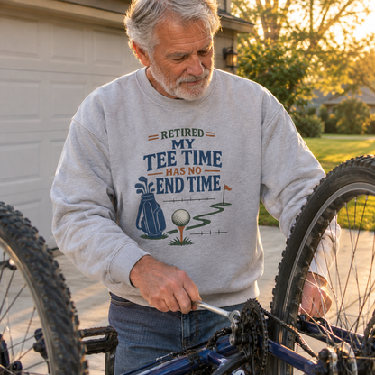 Gray vintage sweatshirt with printed golf slogan worn by senior man repairing a bicycle outdoors
