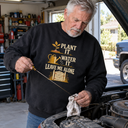 Black vintage sweatshirt printed Plant It Water It Leave Me Alone, worn by senior man in garage