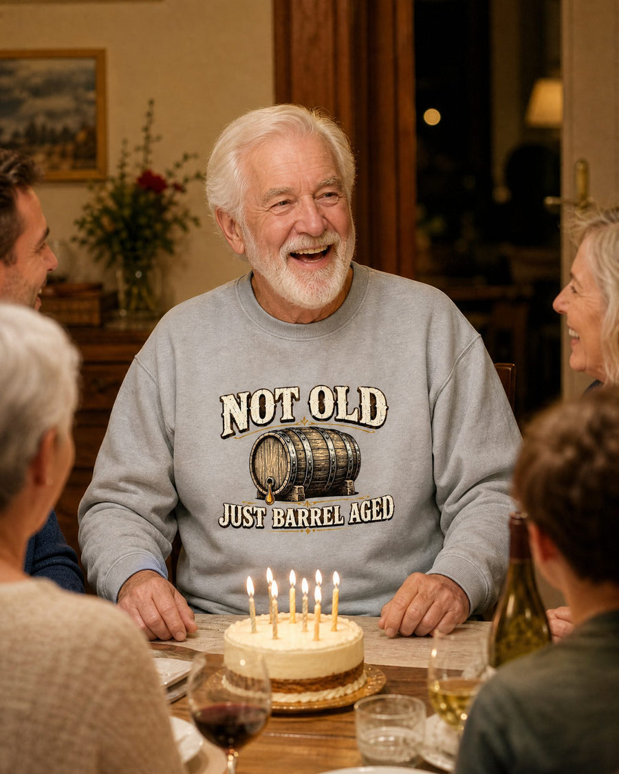 A white-haired man in the sport grey sweatshirt laughing at his birthday dinner