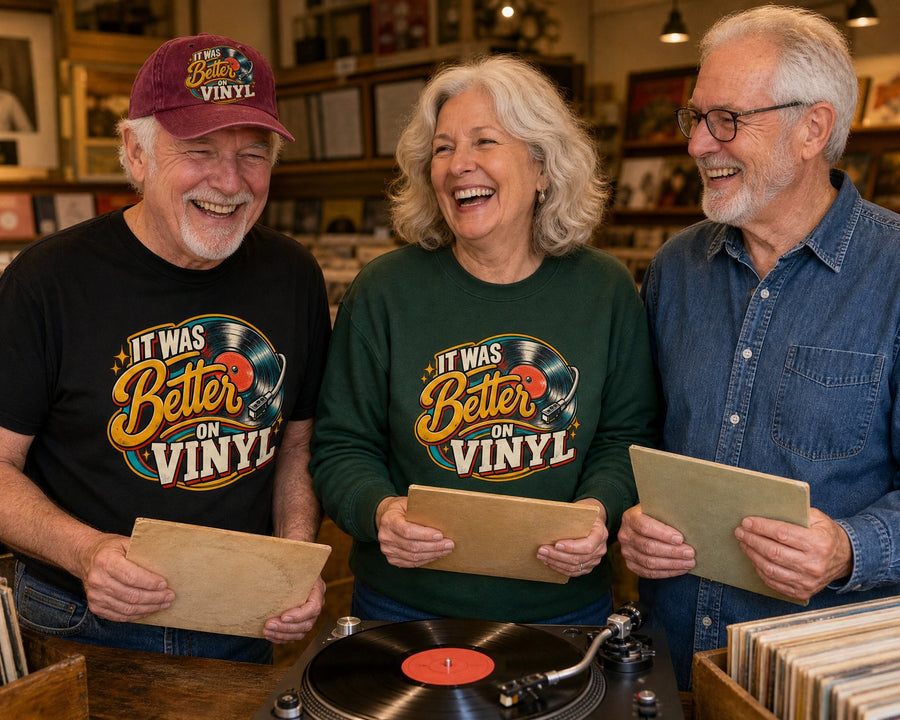 Three friends laughing at a record store counter while a record plays, in the black tee, wine red cap and forest green sweatshirt