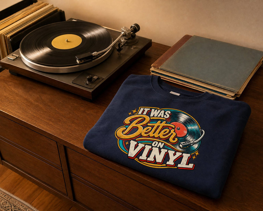 A turntable playing a record beside a stack of records and the navy sweatshirt folded flat