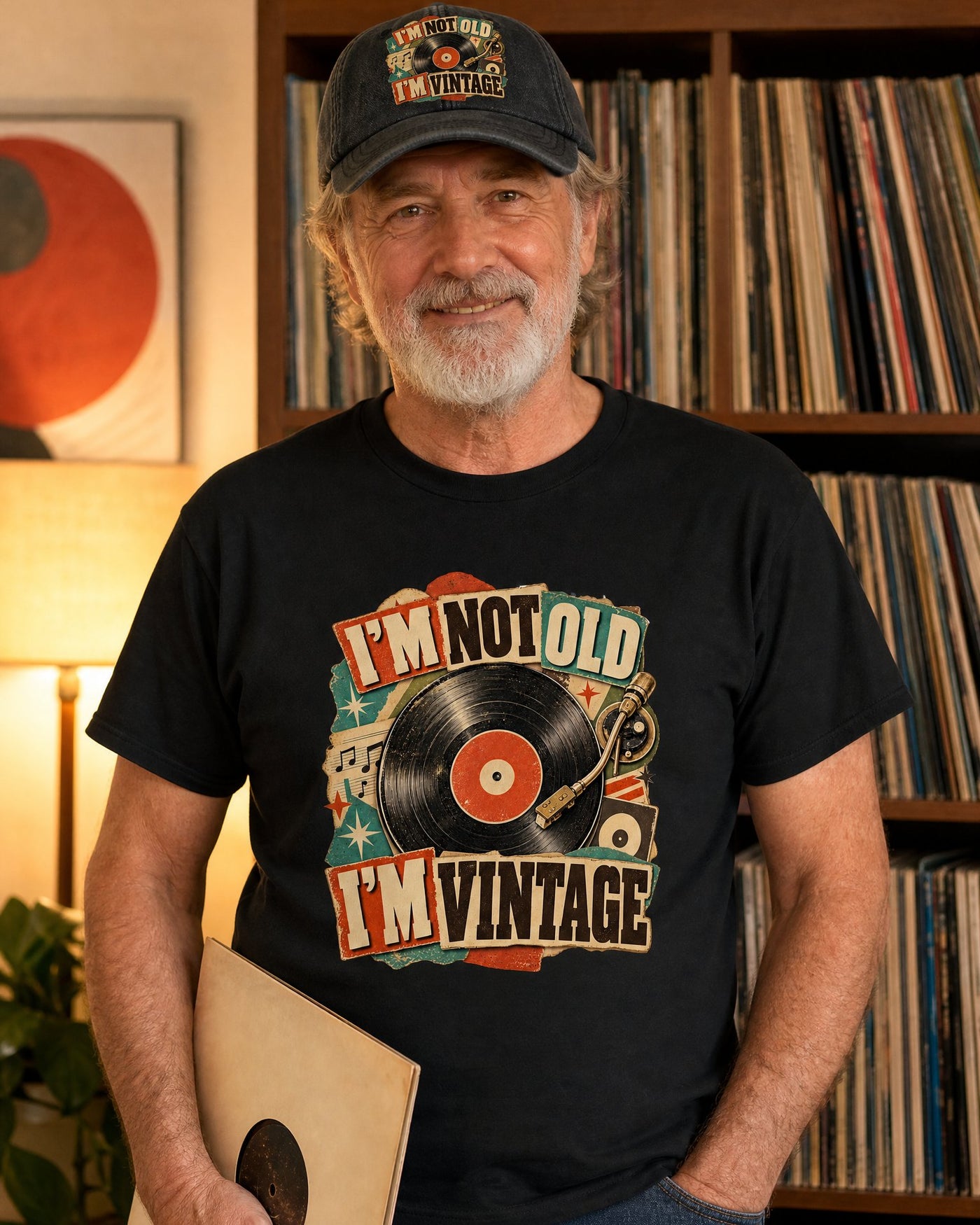 Man in the I'm Not Old I'm Vintage black tee and black cap in front of his record shelf, holding an LP